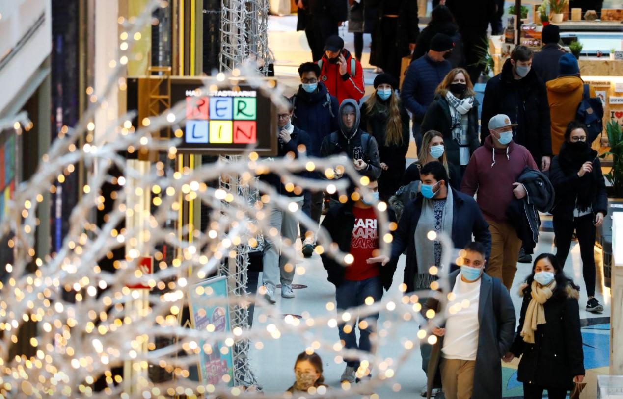 People wear protective face masks as they walk beside Christmas decoration at a shopping mall - Avaz