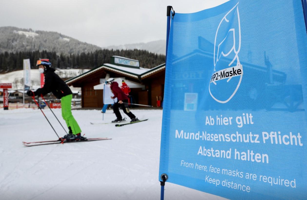 Skiers wear protective face masks and practise social distancing as they pass a sign on the way to a chairlift as the spread of the coronavirus disease (COVID-19) continues in Flachau, Austria January 13, 2021. - Avaz