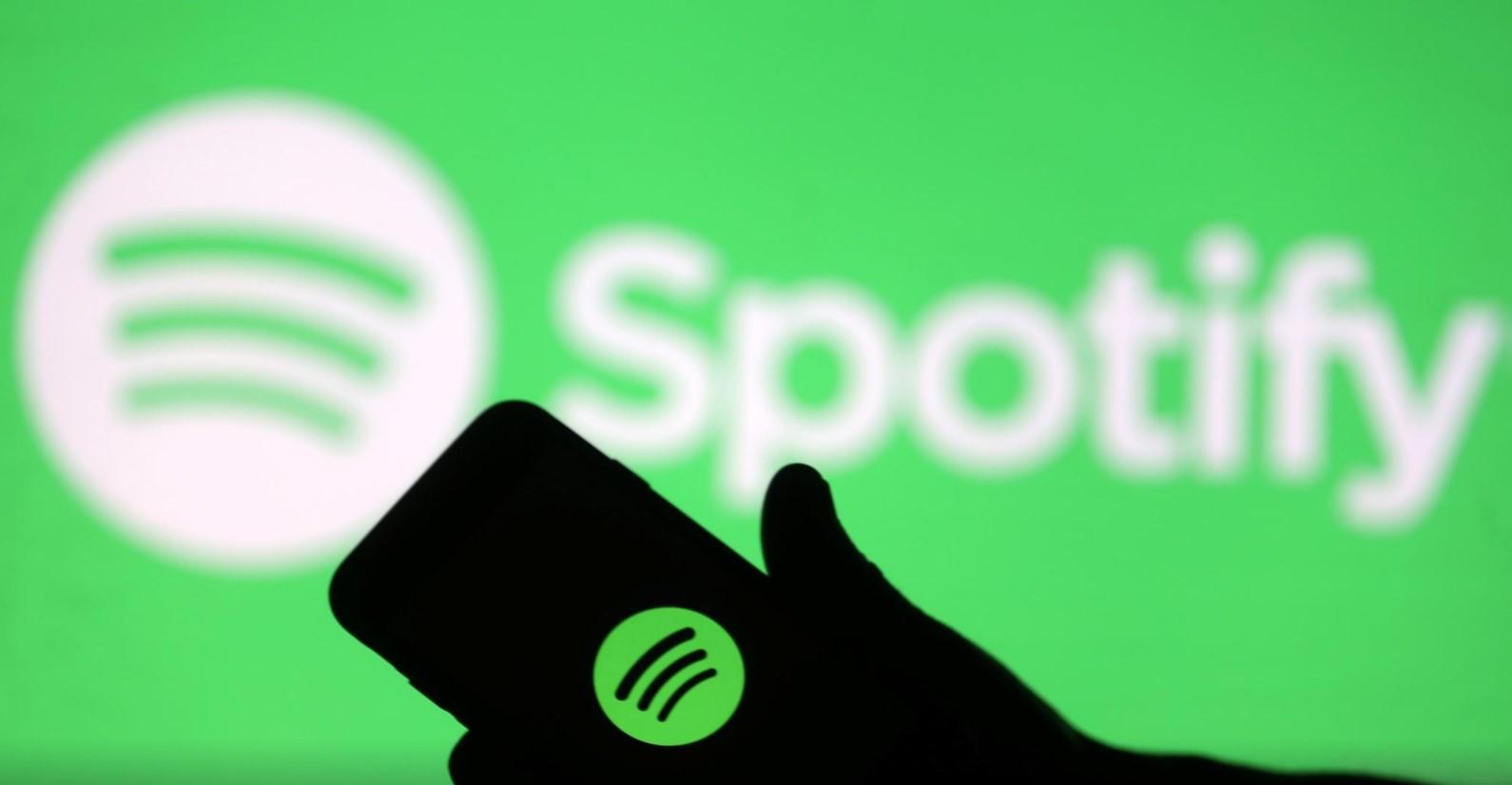 A smartphone is seen in front of a screen projection of Spotify logo, in this picture illustration taken April 1, 2018. - Avaz