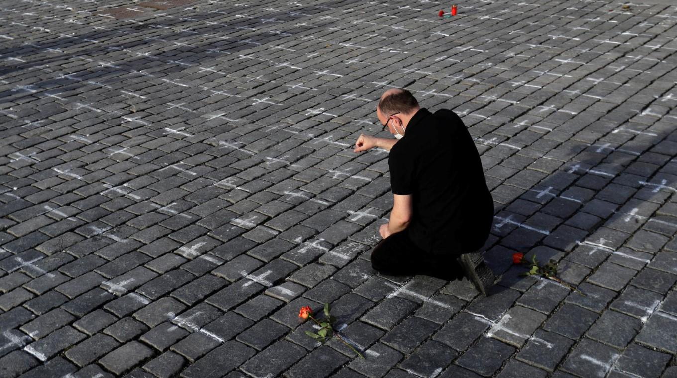 A man mourns for his deceased loved one at the Old Town Square where thousands of crosses have been painted on a pavement to commemorate the first anniversary since the death of the first Czech coronavirus disease (COVID-19) patient in Prague, Czech Republic, March 25, 2021. Picture taken March 25, 2021. - Avaz