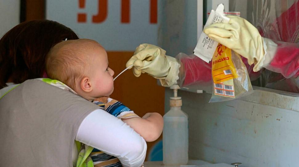 A medic performs a Covid-19 coronavirus swab test on a child in Jerusalem - Avaz