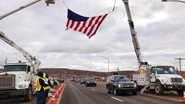 In this photo provided by the Navajo Nation Office of the President and Vice President, tribal utility workers hiost a flag above a funeral procession route for former Navajo President Peterson Zah - Avaz